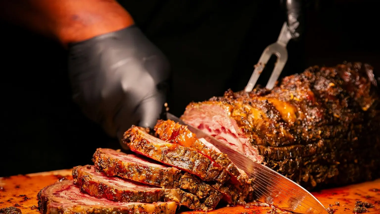 A person cutting a large piece of meat on a cutting board
